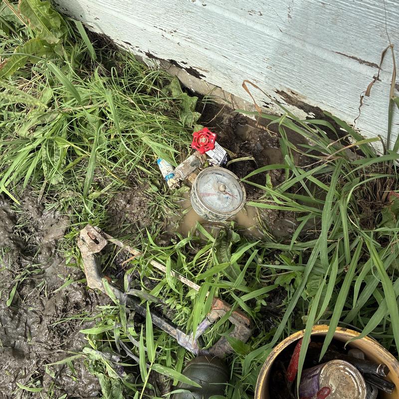 Water meter and valve in muddy yard with leak repair