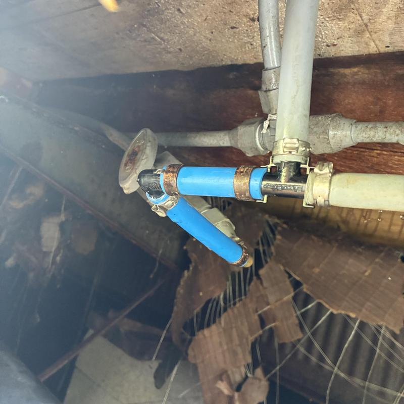 Blue water supply pipe with metal fittings in crawlspace