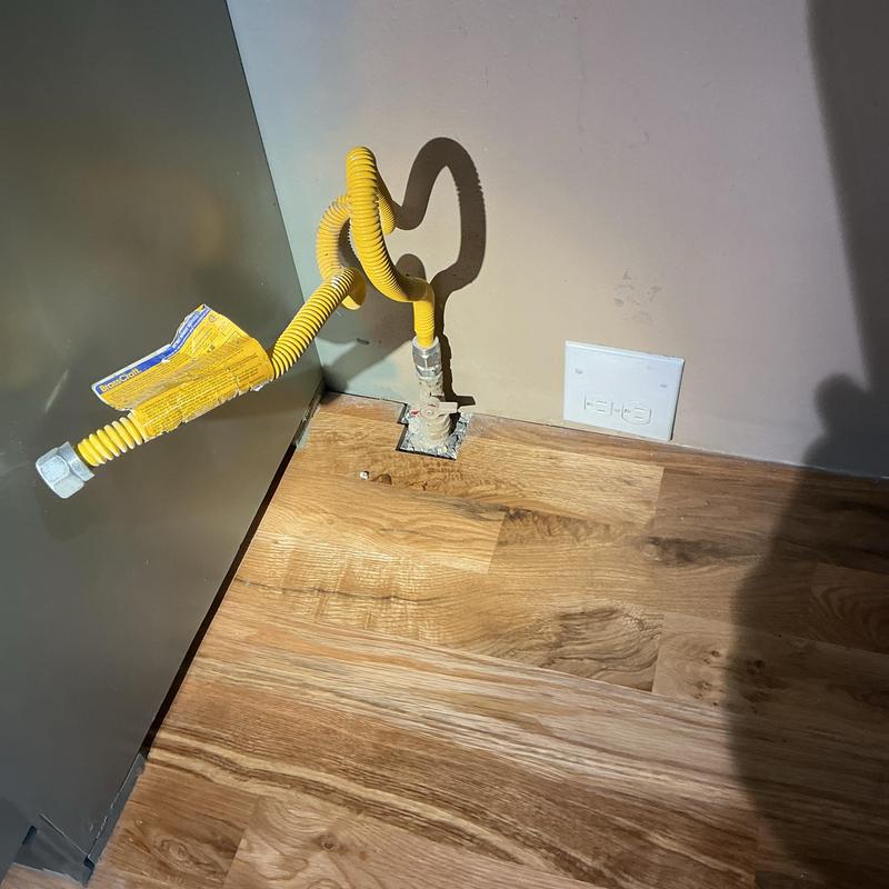 Gas stove flexible connector near wall outlet on wood floor Gas stove flexible connector near wall outlet on wood floor