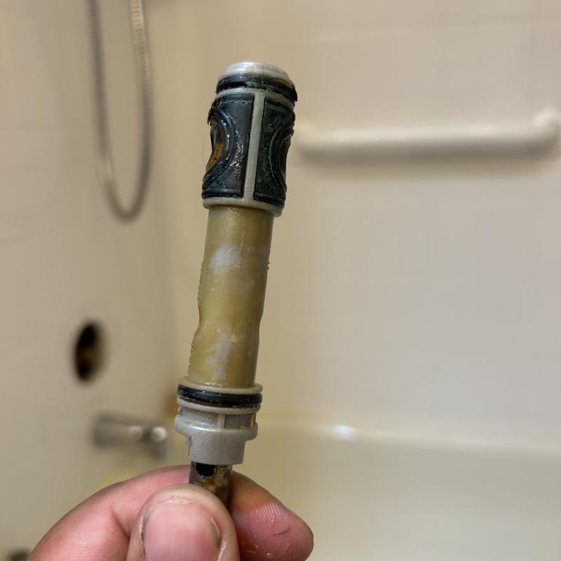 Shower valve cartridge held by technician in bathroom Shower valve cartridge held by technician in bathroom