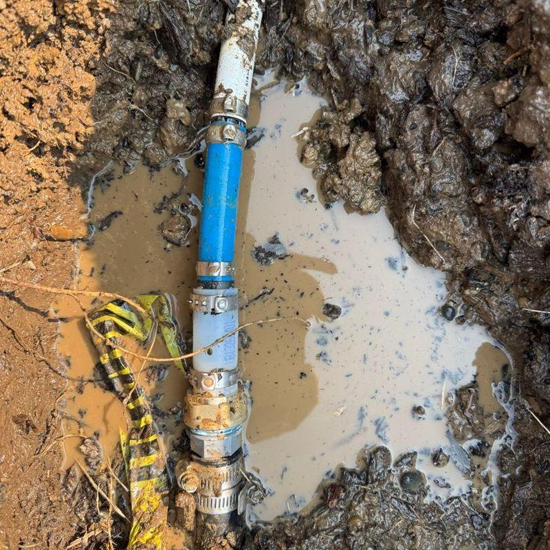 Main water line with repair clamp in muddy trench