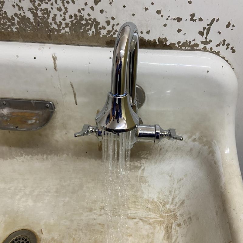 Commercial faucet with running water in men's room sink Commercial faucet with running water in men's room sink