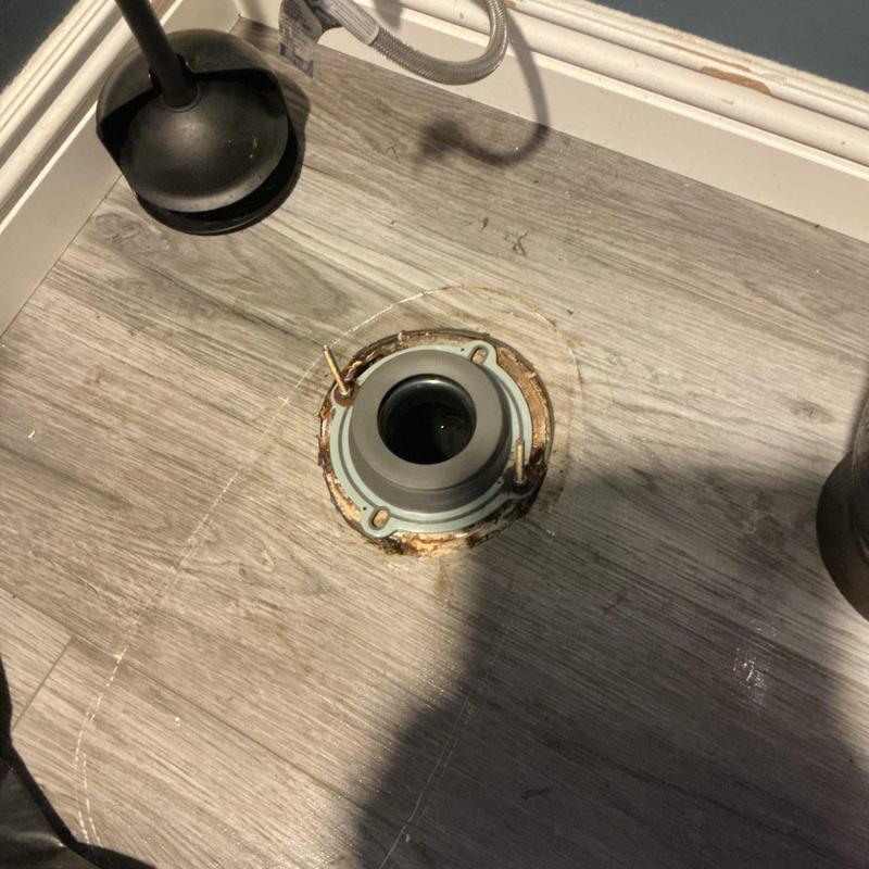 Toilet flange with broken mounting bolts in bathroom floor