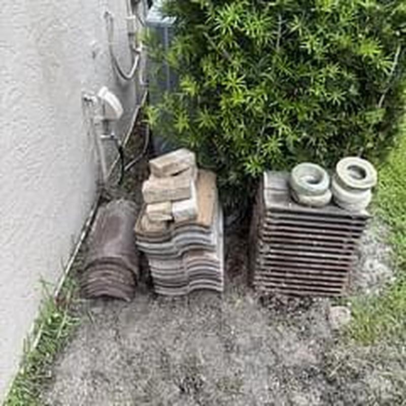 Roof tiles and vents stacked beside house wall