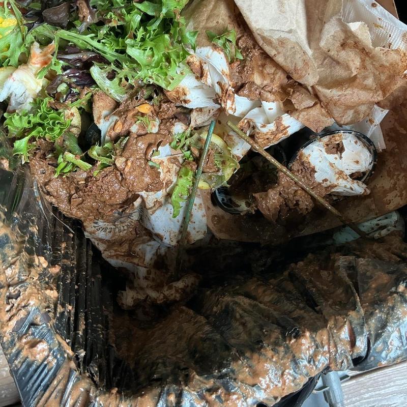 Trash bin with spilled salad and muddy debris Trash bin with spilled salad and muddy debris