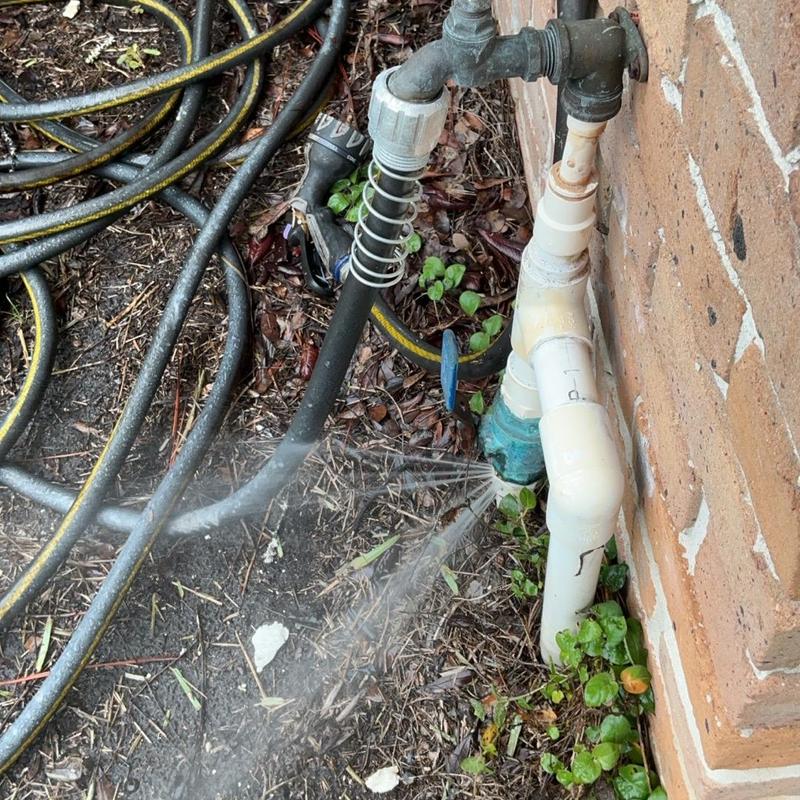 Main waterline PVC pipe with visible leak spray Main waterline PVC pipe with visible leak spray