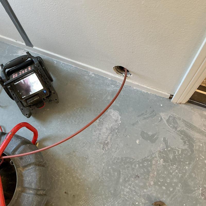 Drain camera inspection with monitor and cable in floor hole