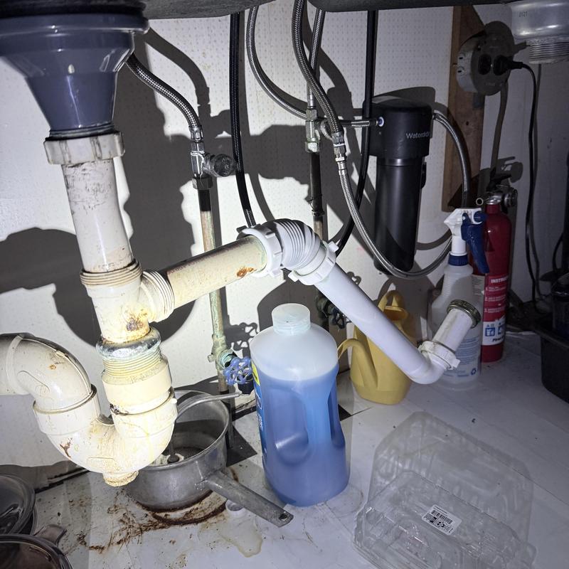 Kitchen drain pipes under sink with cleaning supplies Kitchen drain pipes under sink with cleaning supplies