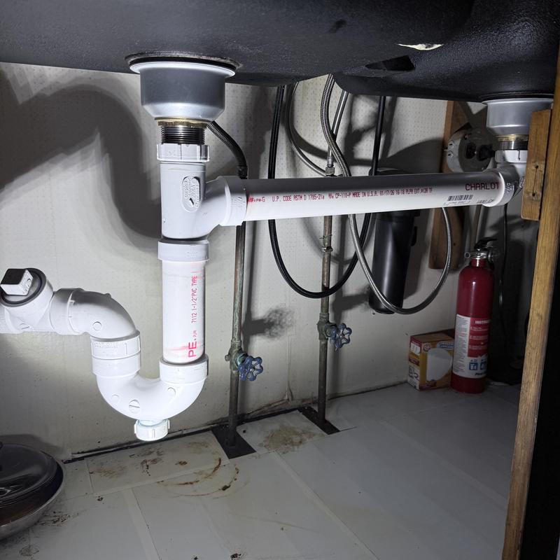 Kitchen sink drain pipes with new PVC fittings under cabinet Kitchen sink drain pipes with new PVC fittings under cabinet