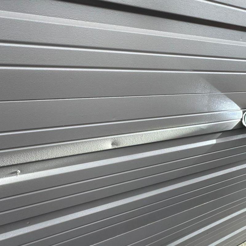 Metal garage door panel with minor dent damage