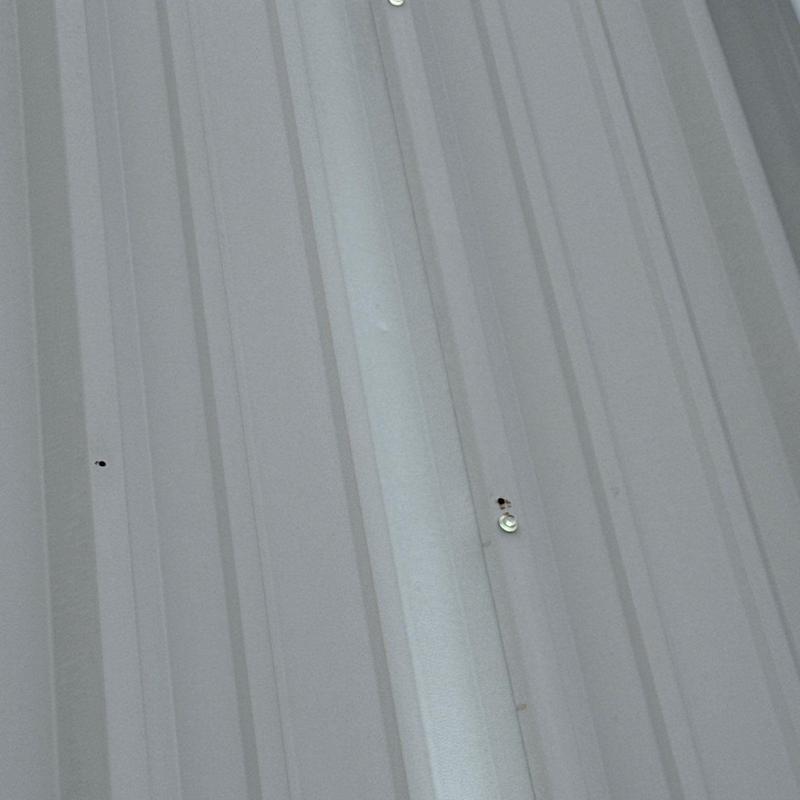 Metal roof panel with hail damage and fasteners