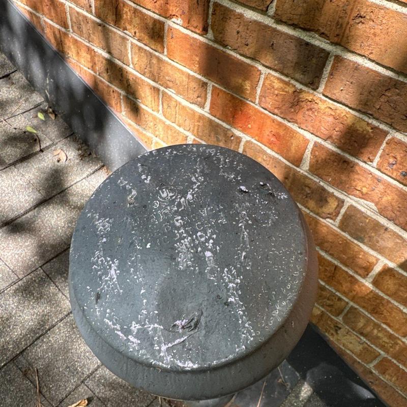 Metal vent cap with weathered surface near brick wall