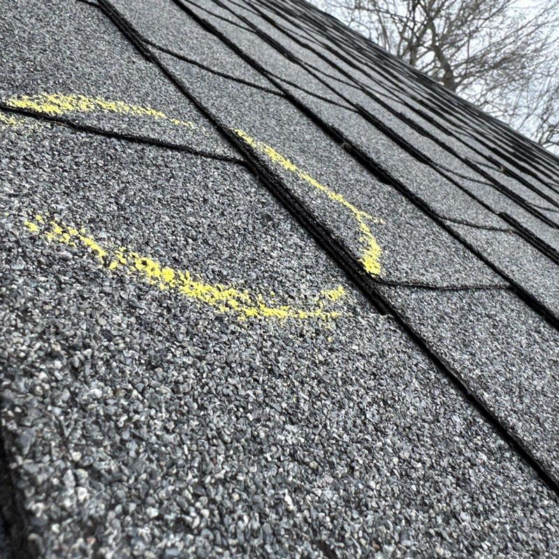 Asphalt shingles with hail damage marked in yellow