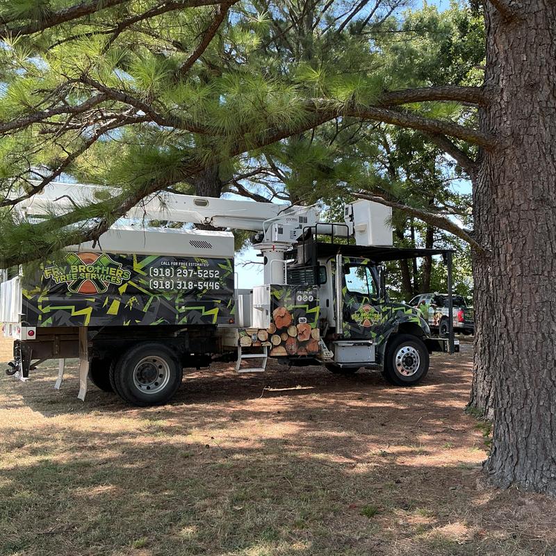 Tree service truck with bucket lift parked under pine trees Tree service truck with bucket lift parked under pine trees