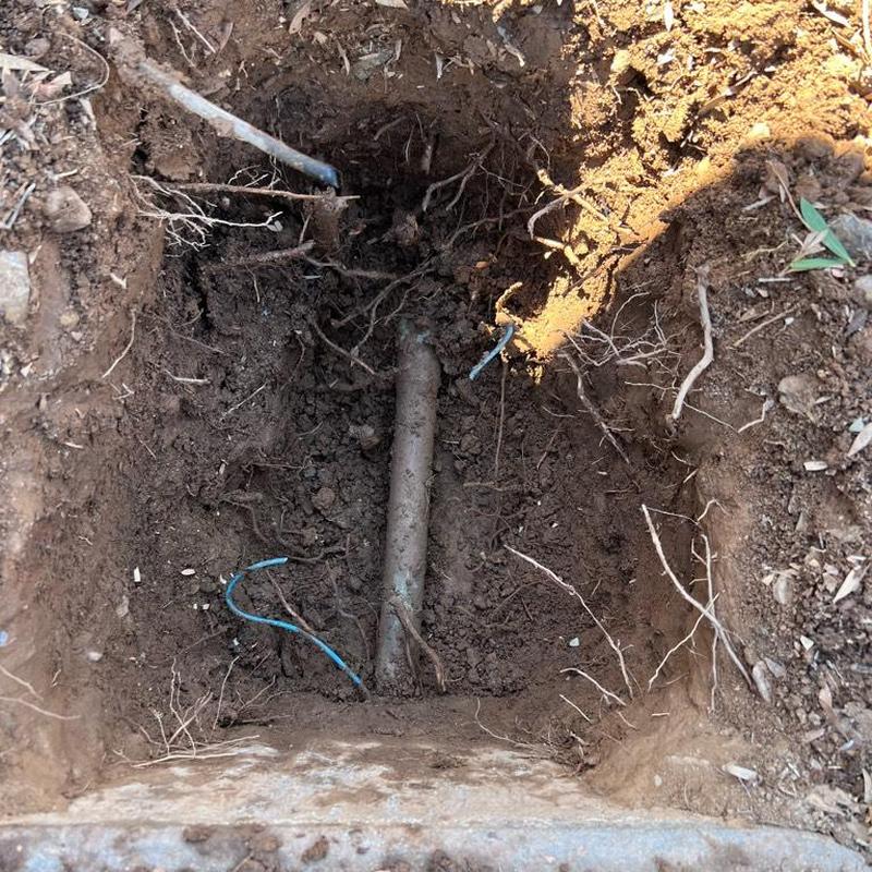 Main waterline excavation with exposed pipe and roots Main waterline excavation with exposed pipe and roots