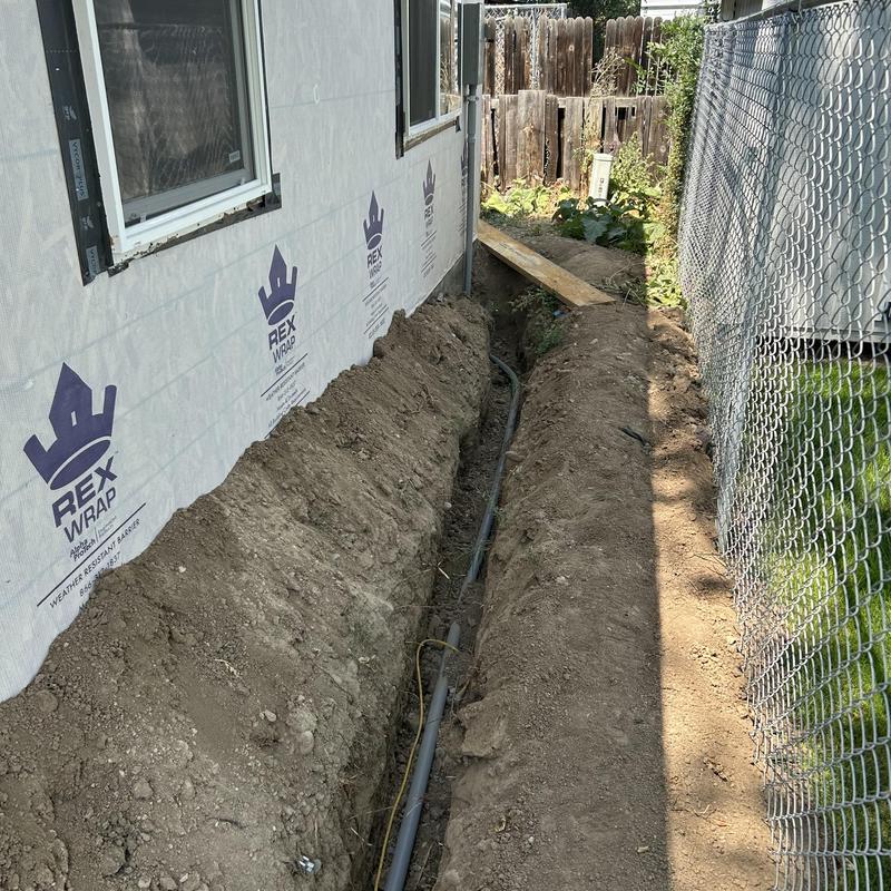 Underground electrical conduit installation beside house