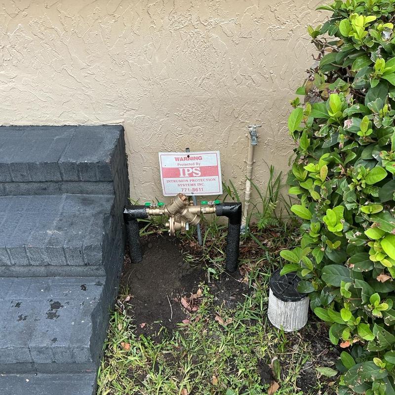 Backflow preventer installation with warning sign outdoors Backflow preventer installation with warning sign outdoors