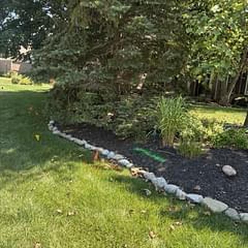 Garden mulch bed with stone border in backyard lawn
