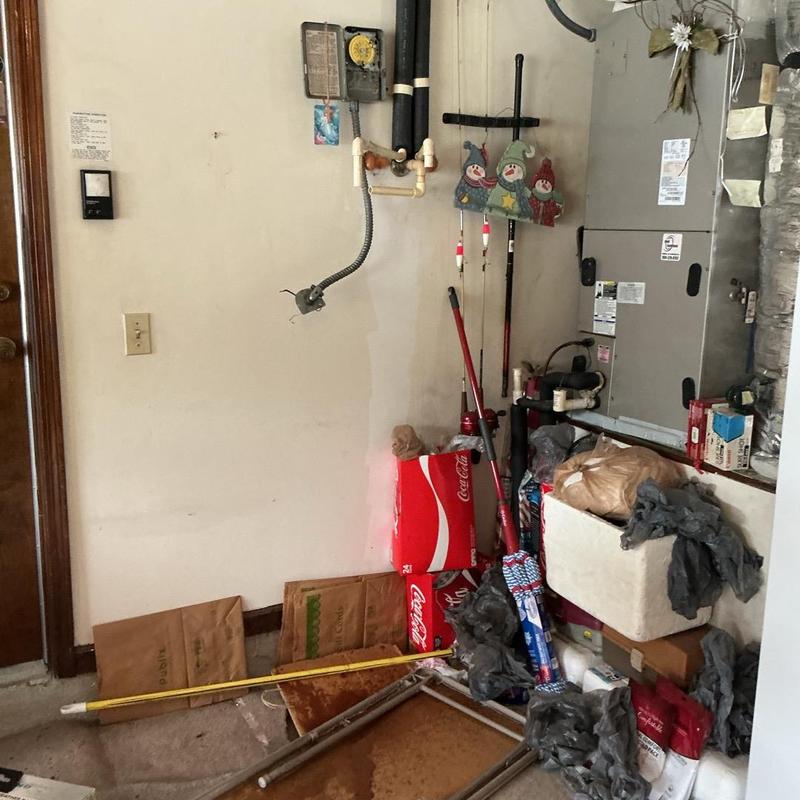 Water heater installation area with plumbing pipes and clutter Water heater installation area with plumbing pipes and clutter