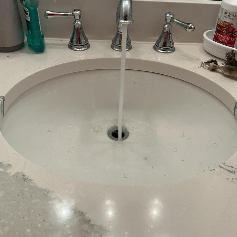 Bathroom sink drain with running water and debris Bathroom sink drain with running water and debris