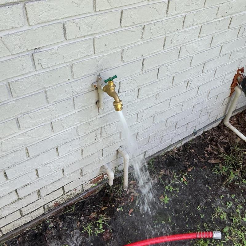 Hose bibb with water flow on white brick wall Hose bibb with water flow on white brick wall