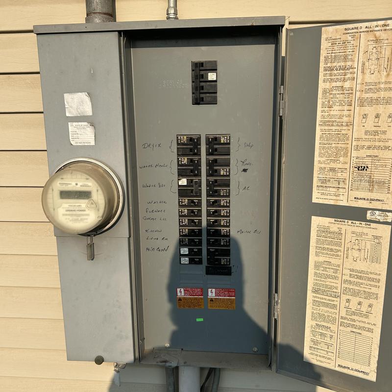 Electrical breaker panel with handwritten labels open on house exterior