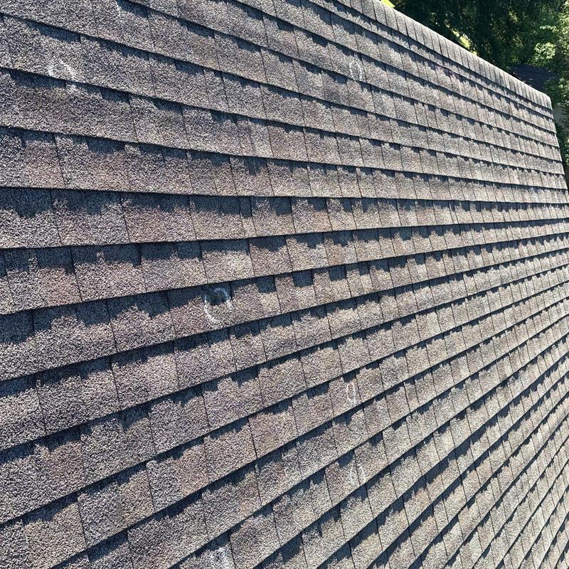 Asphalt roof shingles with visible hail damage spots