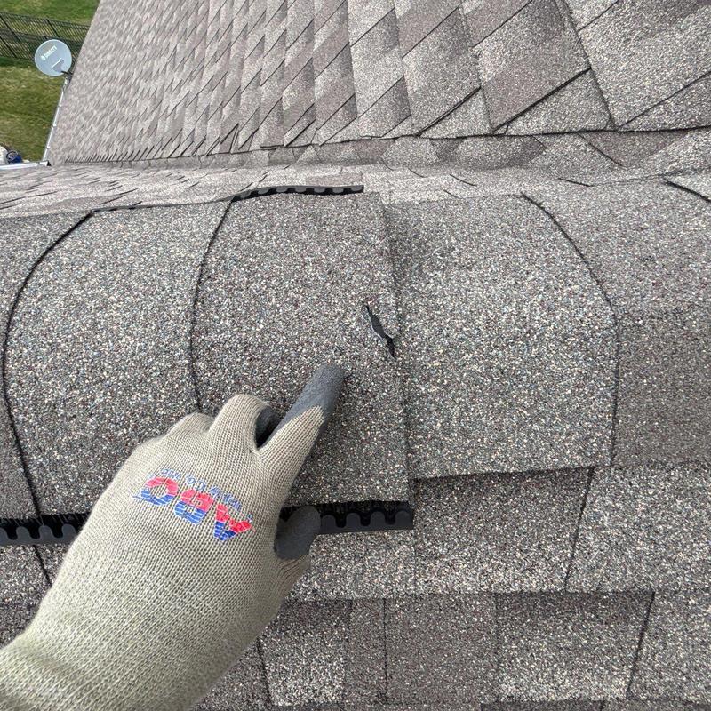 Granule-coated shingles with hail damage on roof ridge