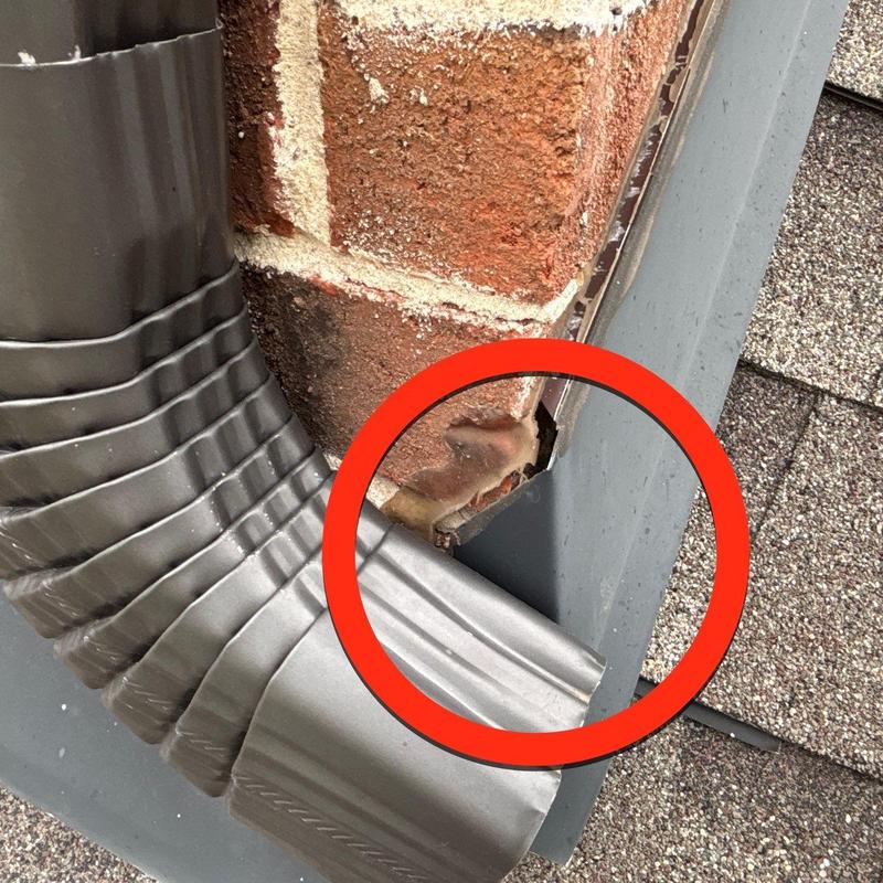 Flashing damage on brick-to-roof junction with downspout
