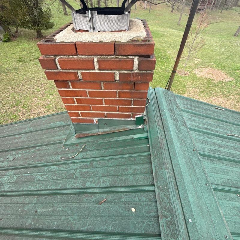 Brick chimney flashing on green metal roof