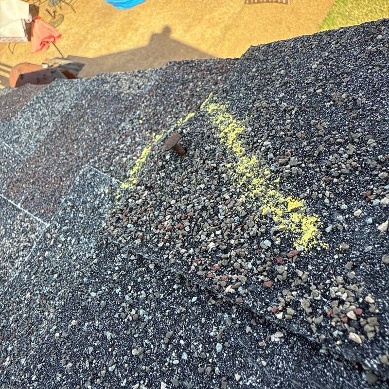 Roof shingles with marked hail damage and nail exposed