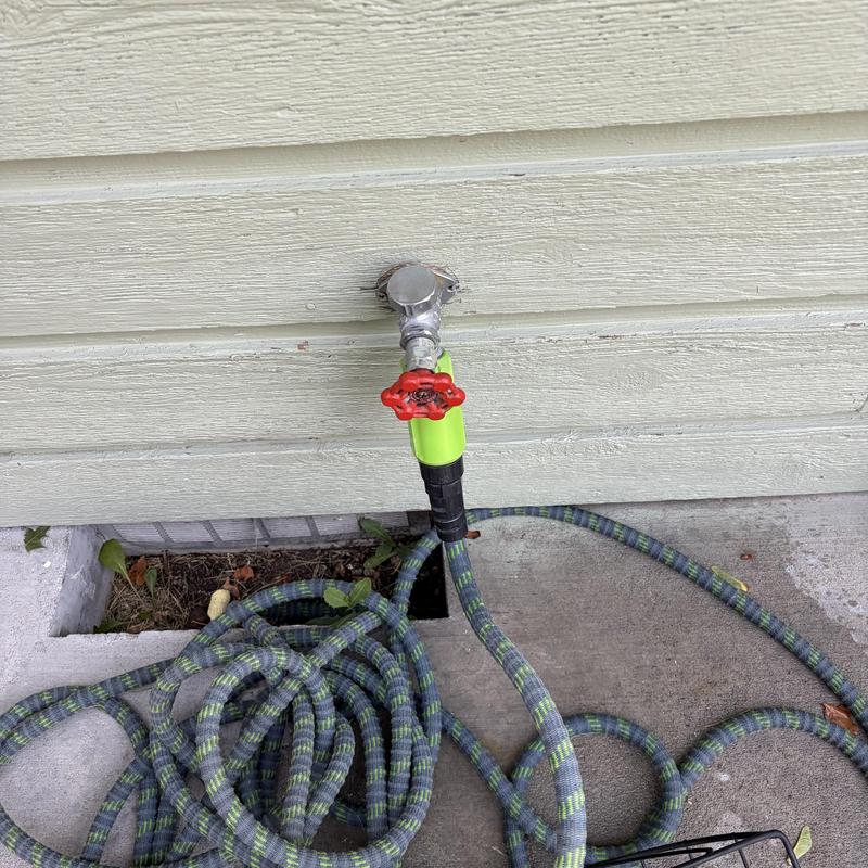 Frost-free hose bib with attached garden hose on wall Frost-free hose bib with attached garden hose on wall