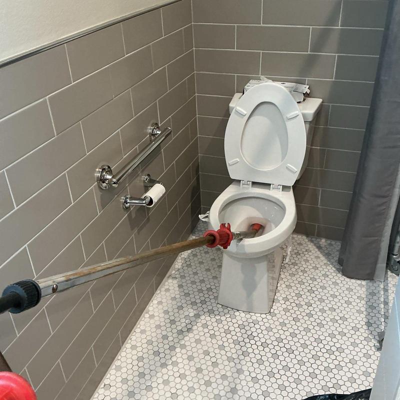 Toilet auger clearing obstruction from toilet trap