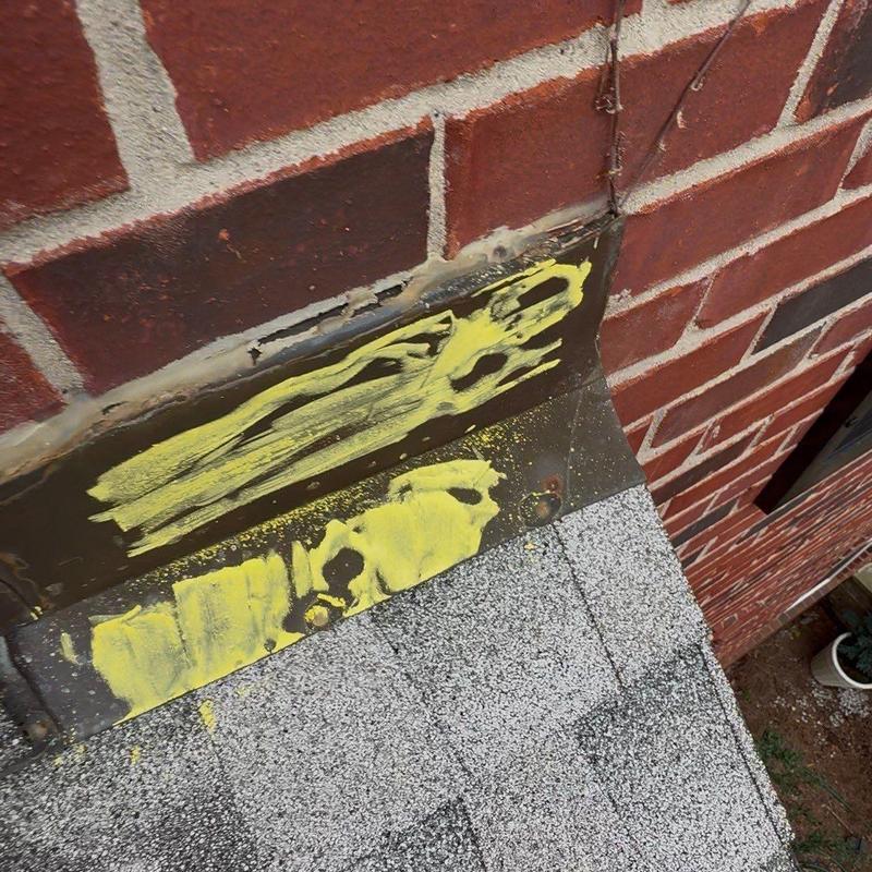 Roof flashing with yellow marking on brick wall