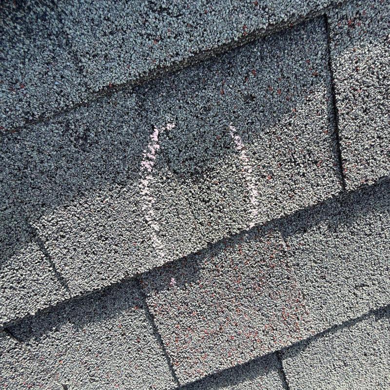 Asphalt roof shingles with hail damage marked for repair