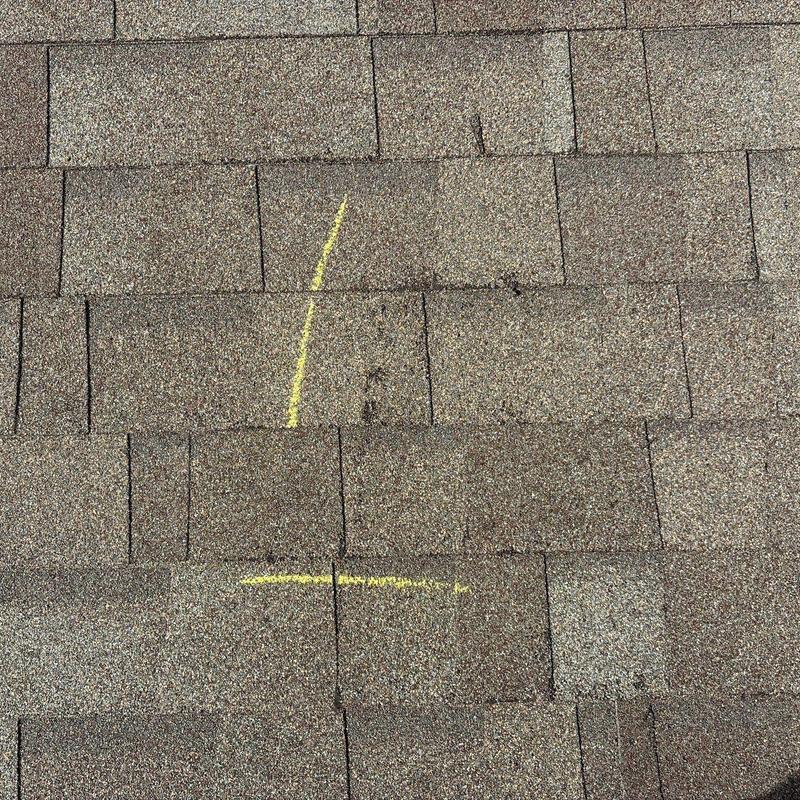 Asphalt roof shingles with marked hail damage spots
