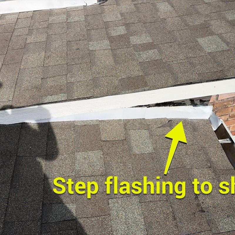 Step flashing on asphalt shingle roof close-up with damage