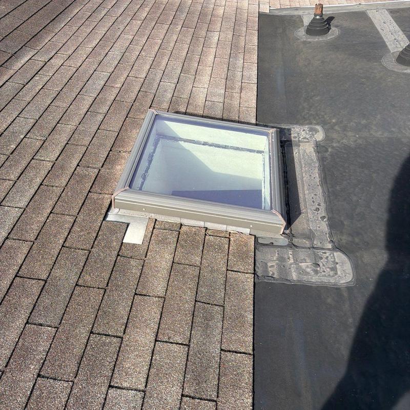 Skylight flashing on shingle and rubber roofing junction