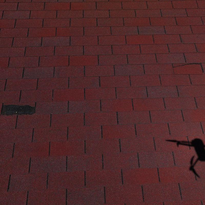 Asphalt roofing shingles with hail damage and repair marks