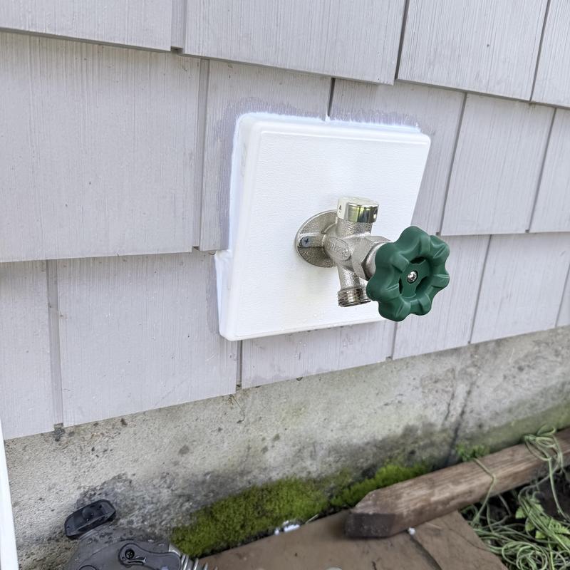Outdoor faucet with frost-proof cover on house exterior Outdoor faucet with frost-proof cover on house exterior