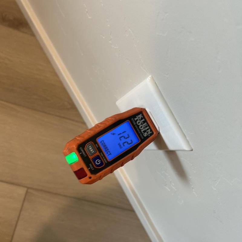 Electrical outlet voltage tester showing correct 122V
