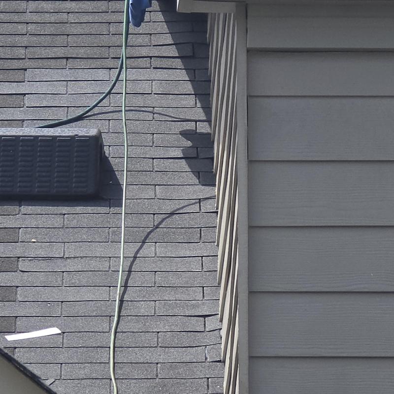 Roof shingles and step flashing along siding wall