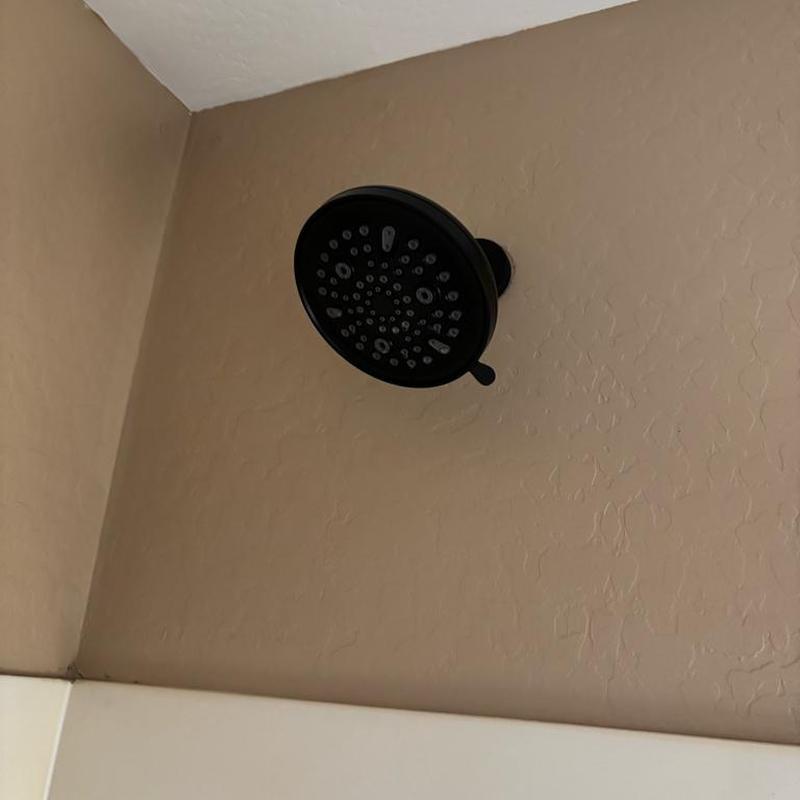 Showerhead installed on textured beige wall above tub