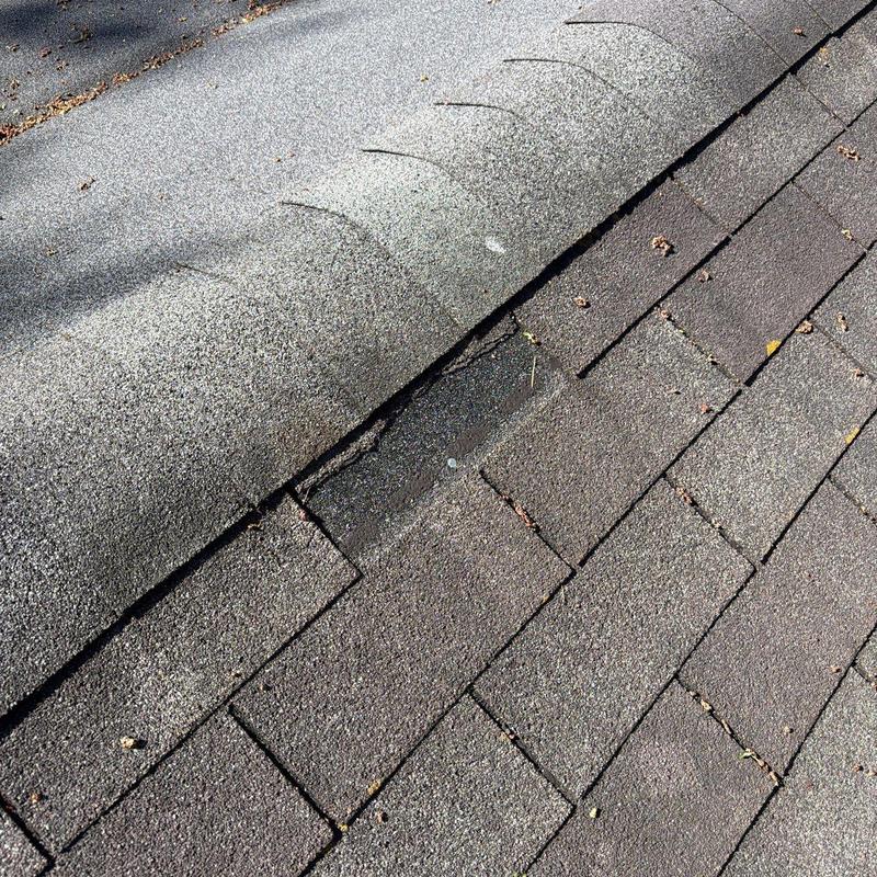 Asphalt roof shingles with hail damage near ridge cap