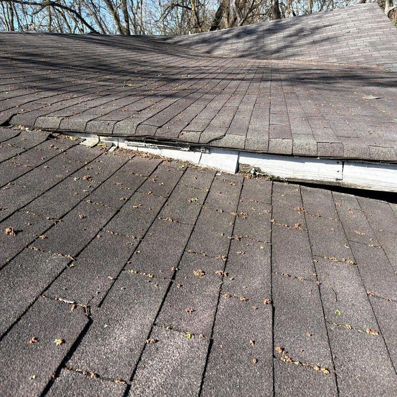 Asphalt shingle roof with damaged ridge cap and decking