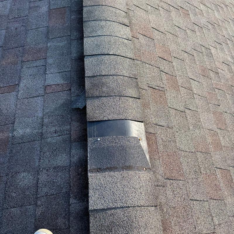 Roof ridge cap with loose shingles and exposed underlayment