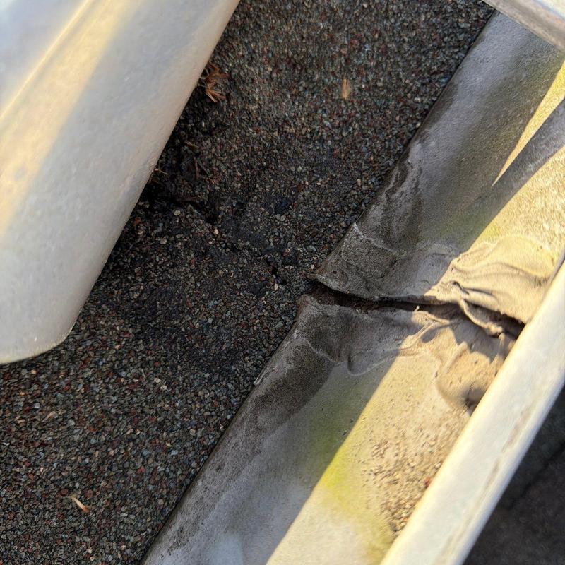 Metal gutter with visible rust and debris buildup