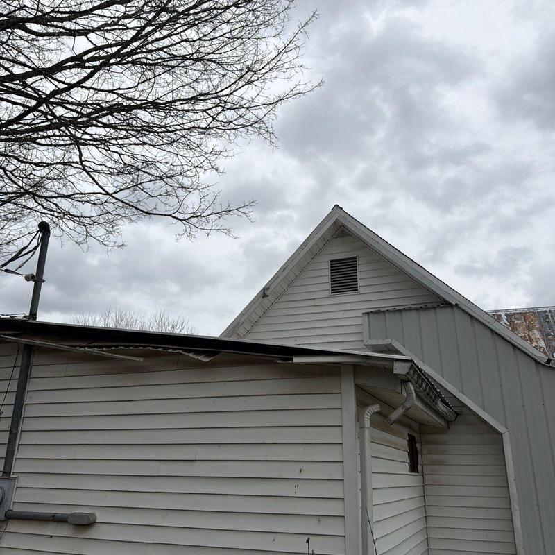 Roof shingles and flashing damaged by hail under cloudy sky