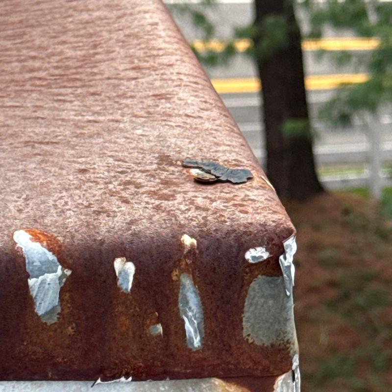 Rust-damaged metal roof edge with flaking paint