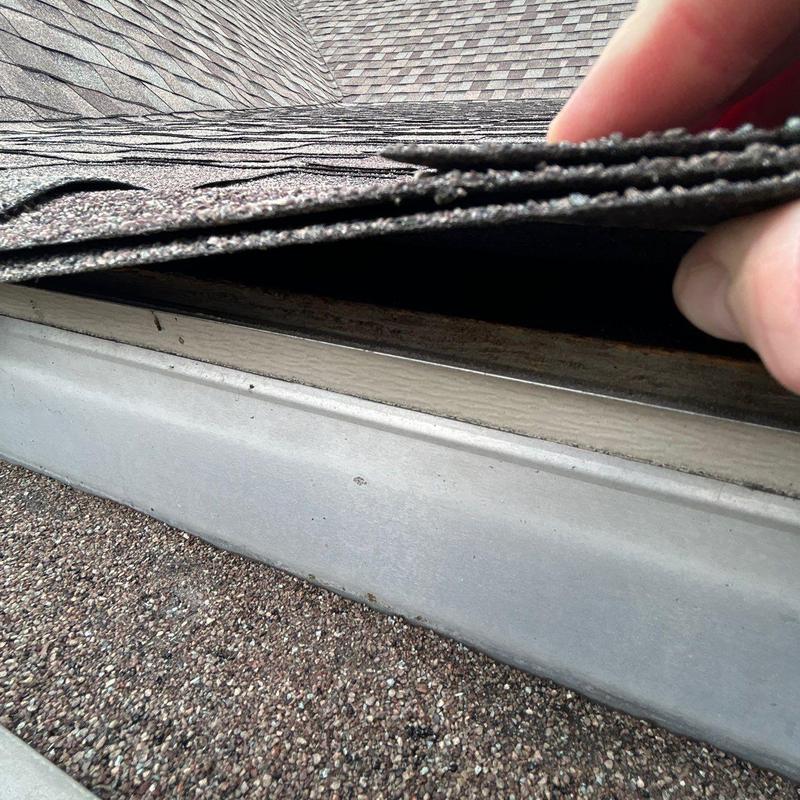 Roof shingles lifted to inspect underlying damage